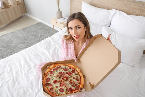 Morning of beautiful young woman with tasty pizza in bedroom — Stock Photo, Image