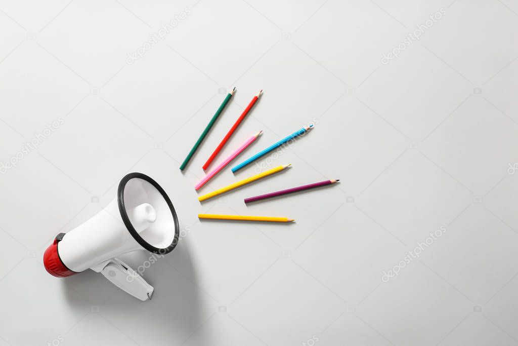 Megaphone with colorful pencils on white background