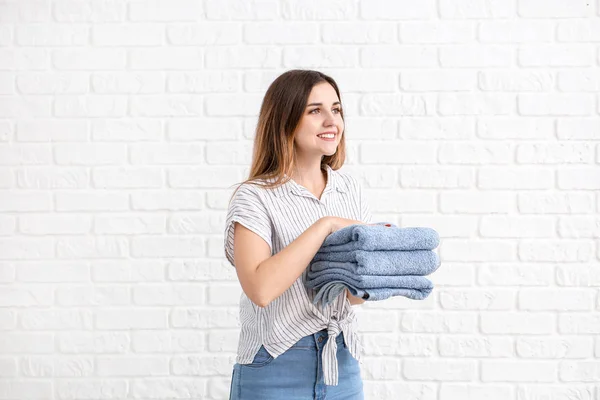 Beautiful young woman with laundry on white brick background — Stock Photo, Image