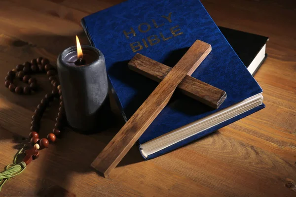 Christian cross, Bible and candle on wooden background — Stok fotoğraf