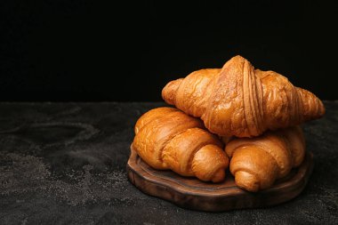 Koyu arkaplanda lezzetli kruvasanlar olan tahta