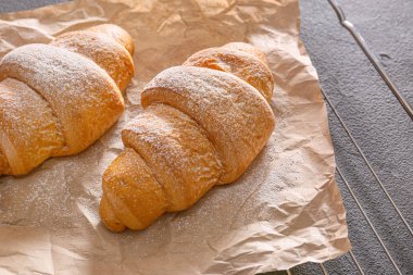 Grid with tasty croissants on dark background, closeup