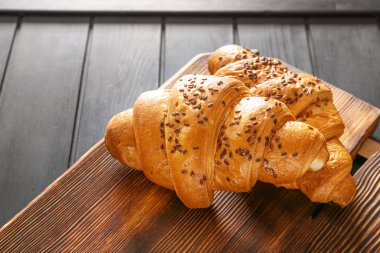 Board with tasty croissants on table, closeup