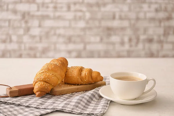 Placa com croissants saborosos e xícara de café na mesa — Fotografia de Stock