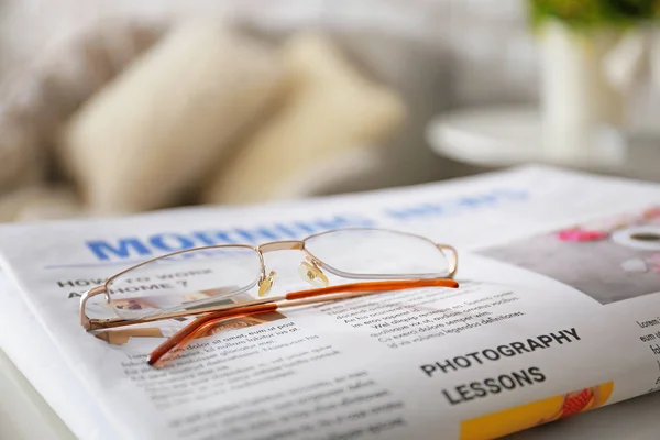 Óculos elegantes com jornal na mesa em casa, close-up — Fotografia de Stock