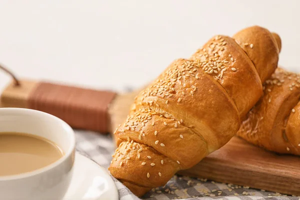 Bord met lekkere croissants en kopje koffie op tafel — Stockfoto