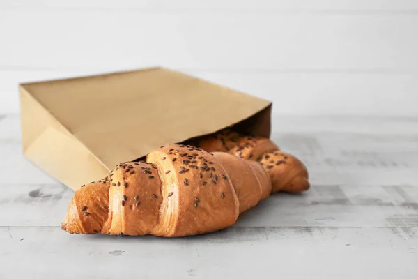 Бумажный пакет с вкусными круассанами на деревянном столе — стоковое фото