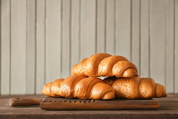 Placa com croissants saborosos na mesa de madeira — Fotografia de Stock