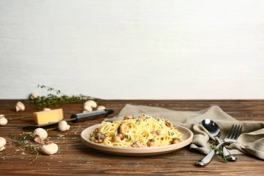 Plate with tasty pasta and mushrooms on wooden table