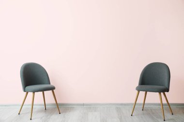 Stylish chairs near color wall in room