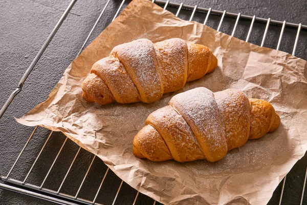 Grid med välsmakande croissanter på mörk bakgrund — Stockfoto