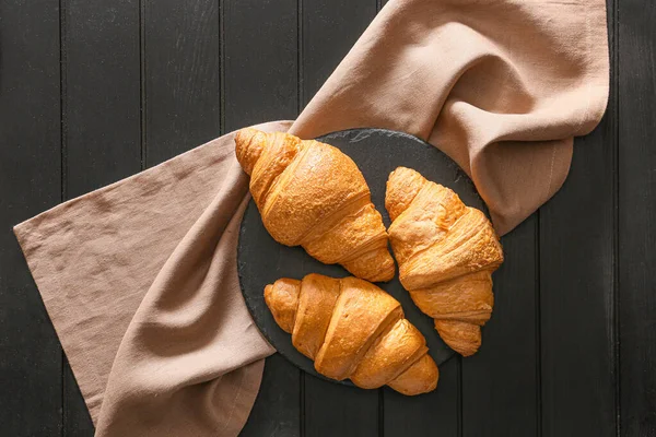 Slate plate with tasty croissants on dark table — Stock Photo, Image