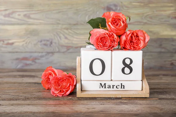 Calendar with date of International Women's Day and flowers on wooden background — Stock Photo, Image
