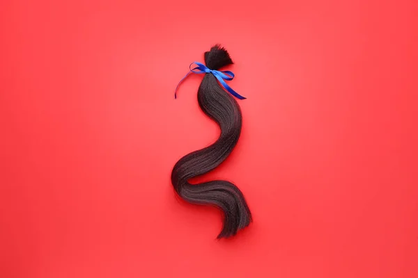 Hair strand with bow on color background — 스톡 사진