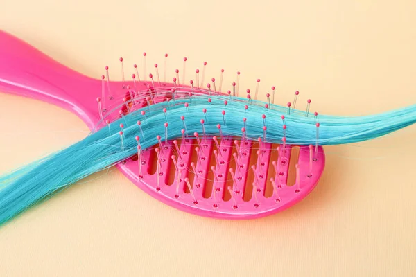 Blue hair strand and brush on color background — Stock Photo, Image