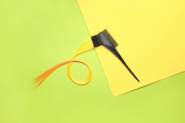 Comb and hair strand on color background