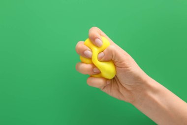 Hand squeezing stress ball on color background
