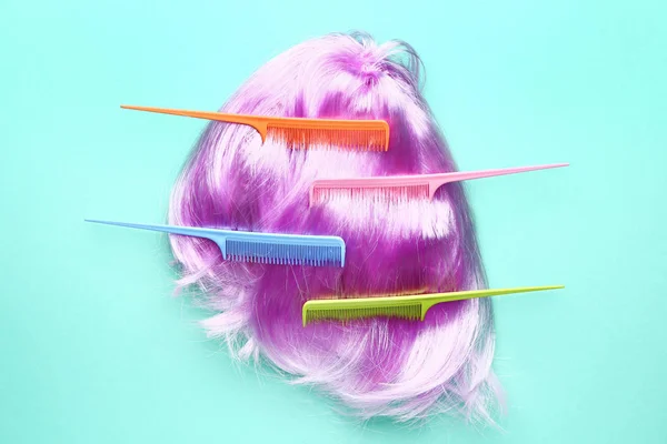 Unusual wig and combs on color background — Stock Photo, Image