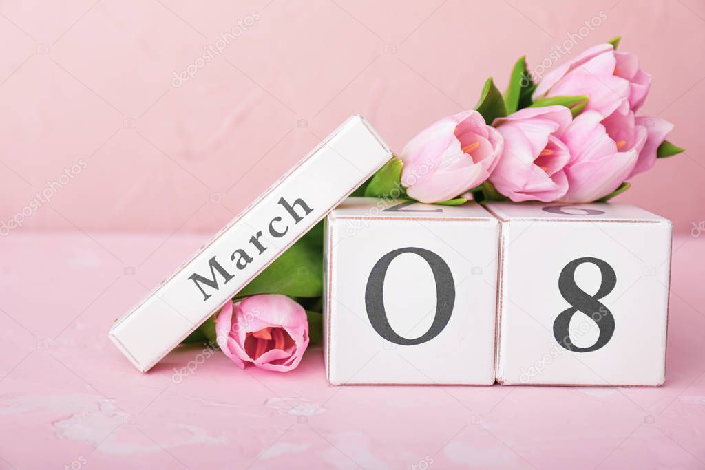 Calendar with date of International Women's Day and flowers on table