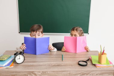 Little pupils sitting at desk in classroom