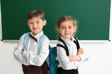 Little pupils near blackboard in classroom