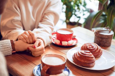 Kafede oturan sıcak çikolatalı genç çift, yakın plan.