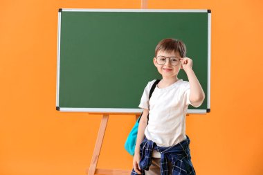 Renkli arka planda tahtaya yakın küçük okul çocuğu.