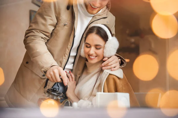 Happy young couple sitting in cafe, view through glass window — Stock Photo, Image