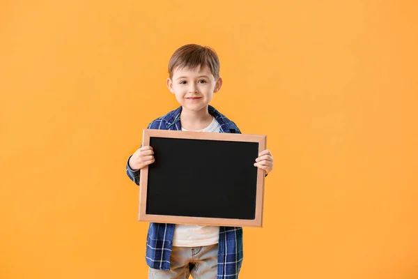 Pequeno estudante com quadro-negro sobre fundo de cor — Fotografia de Stock