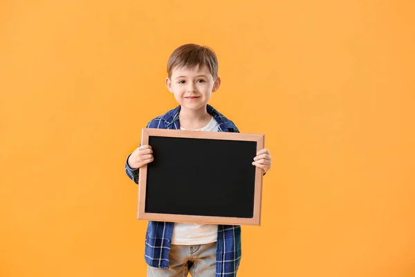 Pequeño colegial con pizarra sobre fondo de color — Foto de Stock