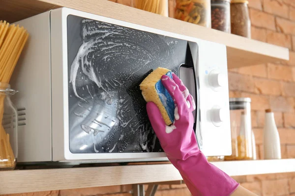 Woman cleaning microwave oven in kitchen