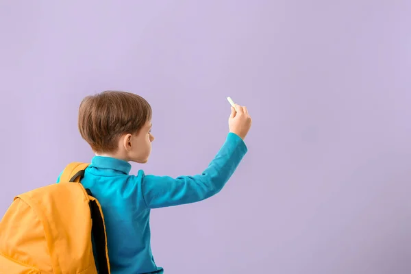 Kleiner Schuljunge mit Kreide auf farbigem Hintergrund — Stockfoto