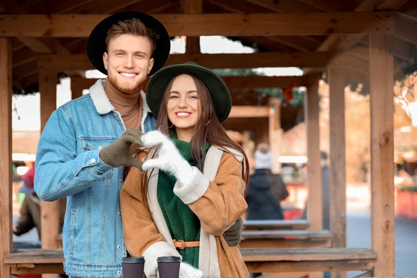 Happy young couple making heart shape with their hands outdoors on winter day — Stock Photo, Image