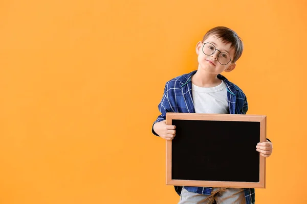 Pequeno estudante com quadro-negro sobre fundo de cor — Fotografia de Stock