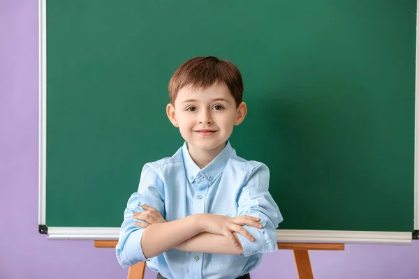 Kleiner Schuljunge in der Nähe der Tafel auf farbigem Hintergrund — Stockfoto