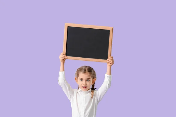 Little schoolgirl with chalkboard on color background — Stock Photo, Image