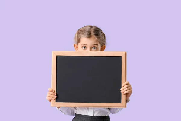 Little schoolgirl with chalkboard on color background — 스톡 사진