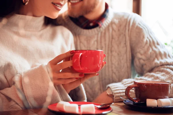 Young couple with cups of hot chocolate sitting in cafe — 스톡 사진