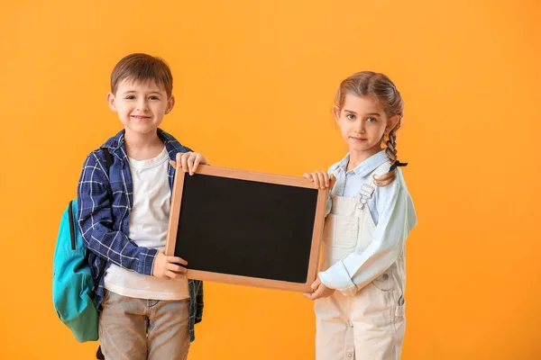 Little pupils with chalkboard on color background — Stock Photo, Image