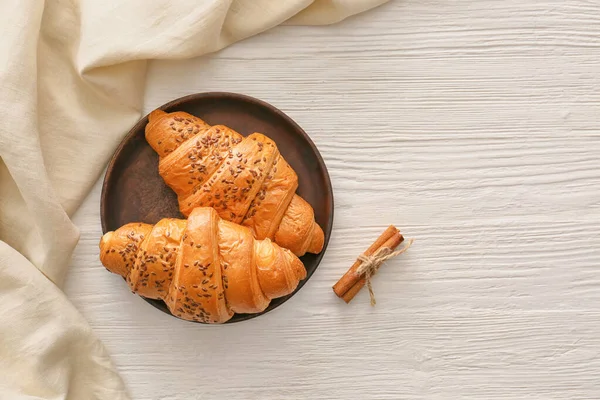 Tallrik med välsmakande croissanter på vitt bord — Stockfoto