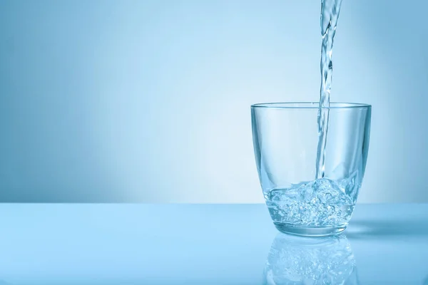 Gieten van zoet water in glas op kleur achtergrond — Stockfoto