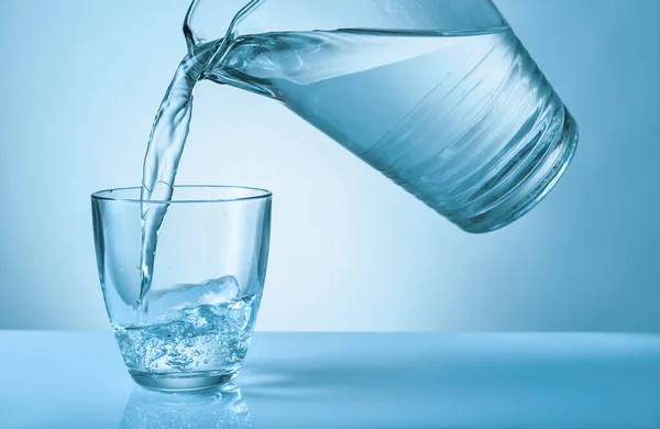Gieten van zoet water in glas op kleur achtergrond — Stockfoto