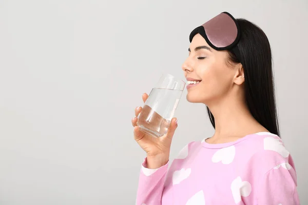 Beautiful young woman with glass of water on light background — Stock Photo, Image