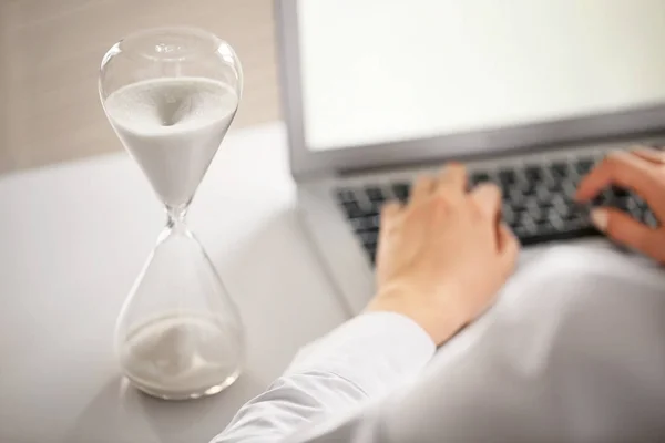 Clessidra e donna che lavorano al computer portatile a tavola in ufficio — Foto Stock