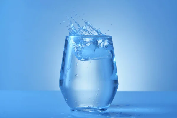 Vaso de agua dulce con salpicadura sobre fondo de color —  Fotos de Stock