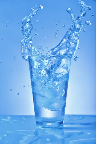 Vaso de agua dulce con salpicadura sobre fondo de color — Foto de Stock