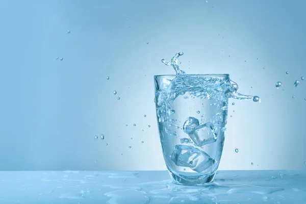 Vidro de água doce com respingo no fundo de cor — Fotografia de Stock