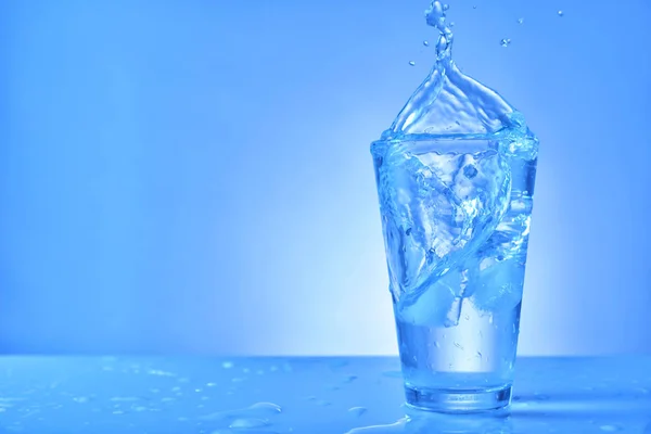 Vaso de agua dulce con salpicadura sobre fondo de color — Foto de Stock