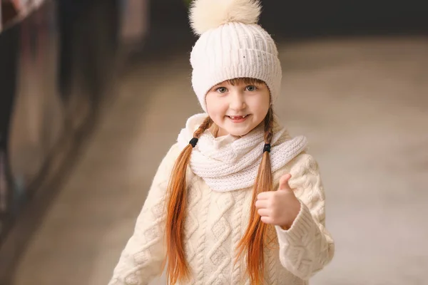 Cute little girl showing thumb-up gesture on skating rink — Stock Photo, Image