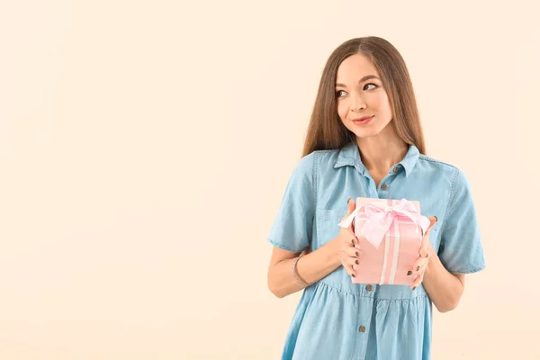 Beautiful young woman with gift on color background. International Women's Day celebration — Stok fotoğraf
